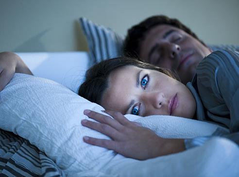 Junge Frau liegt schlaflos im Bett